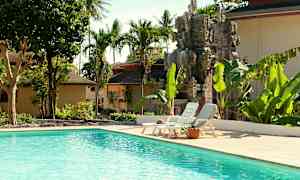 Utomhuspool omgiven av tropiska träd och en dekorativ stenstaty. (AI-genererad text)