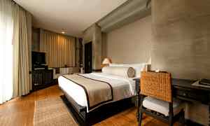 Ett hotellrum med en stor bäddad säng, skrivbord med stol, och en TV i ett mysigt och ljust inrett utrymme. (AI-genererad text)