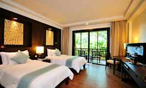 Ett hotellrum med två enkelsängar, en balkong med utsikt över grönska, möbler samt en TV. (AI-genererad text)