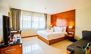 Ett hotellrum med en dubbelsäng, skrivbord, TV och sittmöbler. (AI-genererad text)