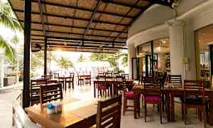 En utomhusrestaurang med tak och träbord stående på en stor terrass. (AI-genererad text)