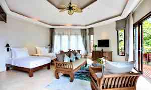 Ett ljust och rymligt hotellrum med två enkelsängar, träinredning och stora fönster med utsikt mot en grönskande balkong. (AI-genererad text)