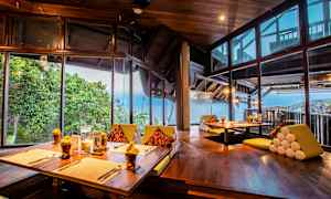 En restaurang med vacker utsikt över havet, med träinredning och stora fönster. (AI-genererad text)