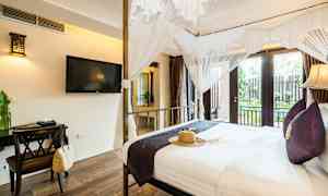 Ett hotellrum med en himmelssäng, TV på väggen och ett skrivbord med dekorativa föremål. (AI-genererad text)