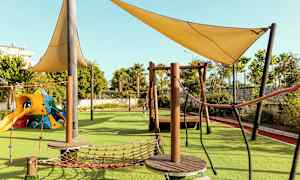 Lekplats med klätterutrustning och skuggande segel. (AI-genererad text)