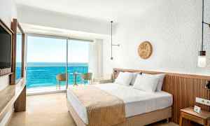 Hotellrum med en dubbelsäng och balkong med utsikt över havet. (AI-genererad text)