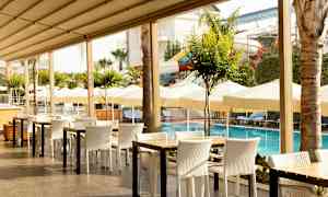 Utomhusrestaurang vid en pool med parasoller och solstolar i bakgrunden. (AI-genererad text)