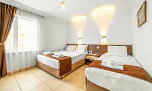 Hotellrum med två separata sängar, ljus insredning och en fönster med mörka gardiner. (AI-genererad text)