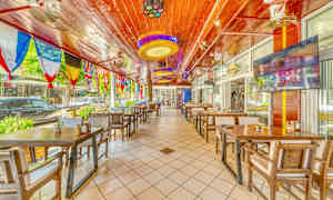 Restaurang med träbord och stolar samt färgglada flaggor hängande från taket. (AI-genererad text)