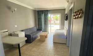 Ett hotellrum med soffa, bord och säng, samt utsikt mot en balkong. (AI-genererad text)