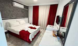 Ett hotellrum med en dubbelsäng, vit och röd inredning samt ett skrivbord med spegel. (AI-genererad text)