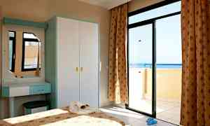 Ett sovrum med en öppen balkongdörr som visar havsutsikten. (AI-genererad text)