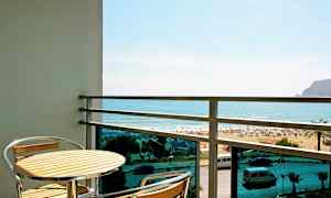 Balkong med ett bord och två stolar, utsikt mot stranden och havet. (AI-genererad text)