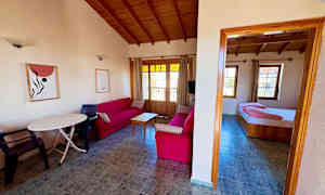 Vardagsrum med röda soffor och trämöbler samt ett anslutande sovrum. (AI-genererad text)