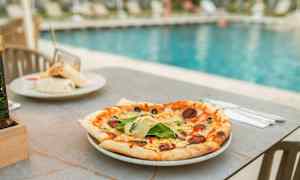 En pizza på ett bord vid en pool. (AI-genererad text)