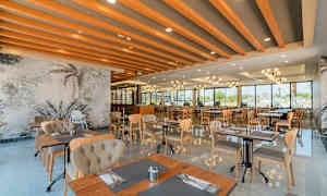 En modern restaurang med stora fönster, trämöbler och dekorativa takbjälkar. (AI-genererad text)