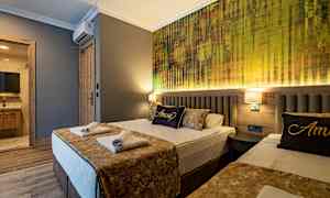 Ett hotellrum med två bäddar, luftigt dekorerat med gyllene accenter och en vägg med modern textur bakom sängarna. (AI-genererad text)