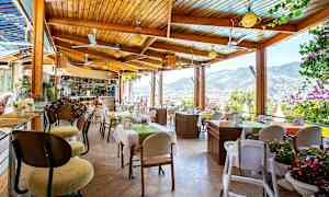 En restaurang med utsikt över bergen och staden, med bord dekorerade med blommor. (AI-genererad text)