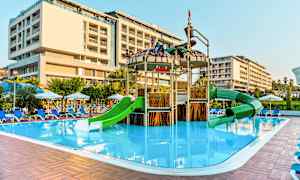 Utomhuspoolområde med en lekplats med gröna rutschkanor och ett intilliggande hotell. (AI-genererad text)