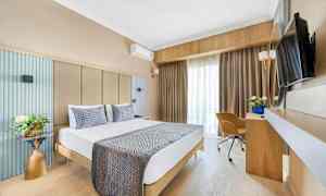 Bild på ett hotellrum med en dubbelsäng, skrivbord, stol och TV. (AI-genererad text)