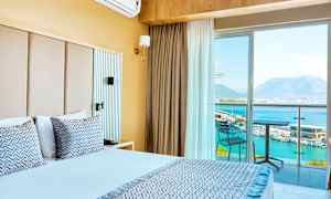 Hotellrum med dubbelsäng, balkong med utsikt över havet och bergen. (AI-genererad text)