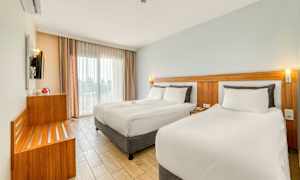 Modernt hotellrum med två sängar, ljusa färger och stora fönster. (AI-genererad text)