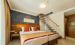 Ett hotellrum med två sängar, dekorativ tapet och en spiraltrappa som leder uppåt. (AI-genererad text)