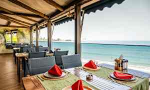 Restaurang med havsutsikt, bord med röda servetter. (AI-genererad text)