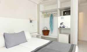 Hotellrum med säng, garderob och en minikyl. (AI-genererad text)