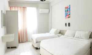 Ett ljust hotellrum med två sängar, ett fönster med gardiner och en garderob. (AI-genererad text)