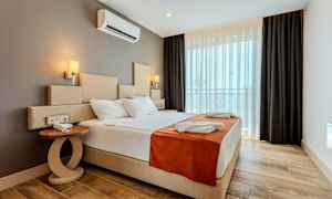 Ett hotellrum med en stor säng, sidobord och fönster med mörkläggningsgardiner. (AI-genererad text)