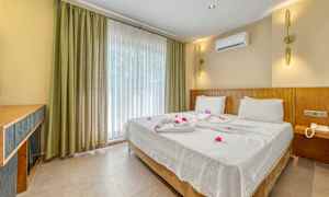 Hotellrum med en dubbelsäng bäddad med vita lakan och dekorerad med blommor. (AI-genererad text)