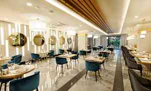 Bild av en elegant restaurang med blå och svarta stolar, marmorgolv och gulddetaljer. (AI-genererad text)