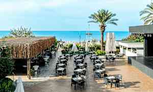 En utomhusrestaurang med bord och stolar, belägen nära havet. (AI-genererad text)