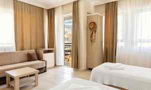 Ett hotellrum med två sängar, en soffa och balkongdörr. (AI-genererad text)