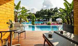 Uteplats framför en pool med solstolar, bord och växter. (AI-genererad text)