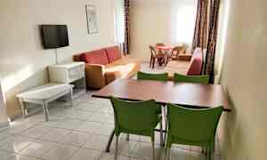 Ett vardagsrum med soffor, ett matbord med stolar och en väggmonterad tv. (AI-genererad text)