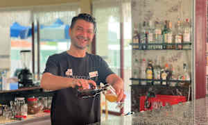 En bartender häller upp en drink vid en bar. (AI-genererad text)