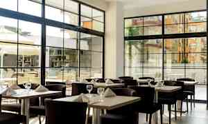 Restaurang med dukade bord och stora fönster. (AI-genererad text)