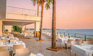 Utomhusrestaurang med havsutsikt vid solnedgången. (AI-genererad text)