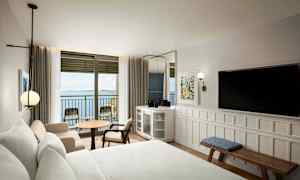 Hotellrum med havsutsikt genom en balkongdörr. (AI-genererad text)