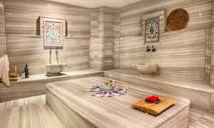 Ett traditionellt hamam med marmorinredning och dekorativa element samt en central plats för tvagning. (AI-genererad text)