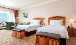 Bild av ett hotellrum med två enkelsängar, sittgrupp och bord. (AI-genererad text)