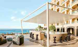 En utomhusbar med sittområde, parasoll och utsikt över havet. (AI-genererad text)