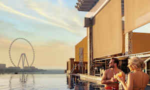 Personer står i en pool med en utsikt över ett stort pariserhjul vid solnedgång. (AI-genererad text)