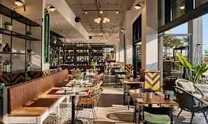 Modernt inredd restaurang med stora fönster och sittplatser. (AI-genererad text)