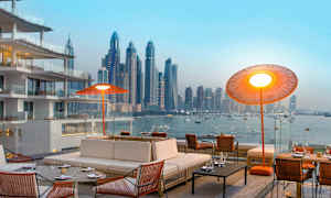 Ett modernt utomhusområde med bekväma sittplatser och utsikt över en stadssilhuett vid vattnet. (AI-genererad text)