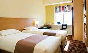 Ett hotellrum med två enkelsängar, en arbetsstation vid ett fönster och moderna möbler. (AI-genererad text)