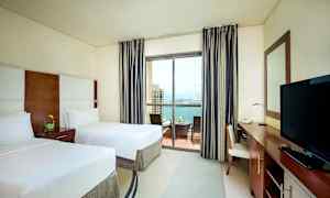 Hotellrum med två enkelsängar, balkong med utsikt över havet. (AI-genererad text)