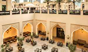 Välutformad innergård med sittgrupper, prydnader av orientaliska valv och belysning, samt omgiven av modern och traditionell arkitektur. (AI-genererad text)